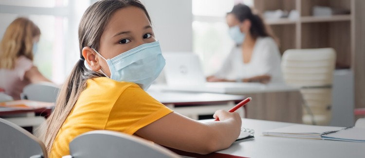 Masked girl sitting at a classroom desk ready to do an assignment. Masked girl sitting at a classroom desk ready to do an assignment.
