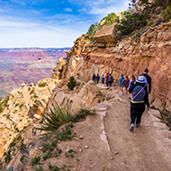 group of girls and women walking on a rocky ledge over a canyon